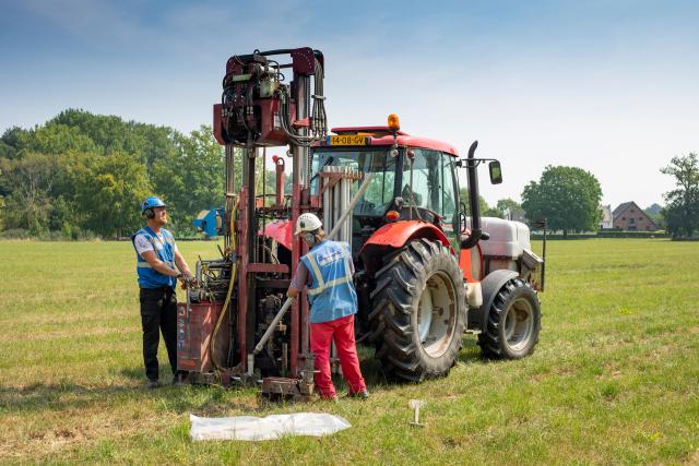 Mensen voeren seismisch onderzoek uit met tractor en daarvoor benodigd apparatuur